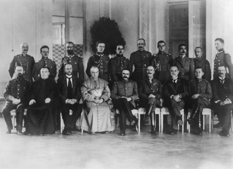 Naczelnik Państwa Józef Piłsudski w towarzystwie członków zagranicznych misji wojskowych w Polsce i oficerów Wojska Polskiego. W I rzędzie widoczni m.in.: Jan Piłsudski (1. z lewej), biskup wileński Jerzy Matulewicz (4. z lewej), Józef Piłsudski (5. z lewej) i Adrian Carton de Wiart (4. z prawej) . W II rzędzie stoi m.in. Walery Sławek (3. z lewej), 1919. Źródło: NAC