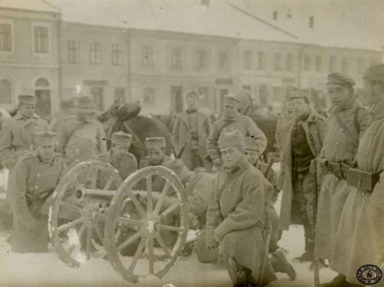 Artylerzyści legionowi przy 70-mm armacie górskiej wz. 1875 na rynku nieznanej miejscowości. Zima, 1914/1915 r. Źródło: CAW