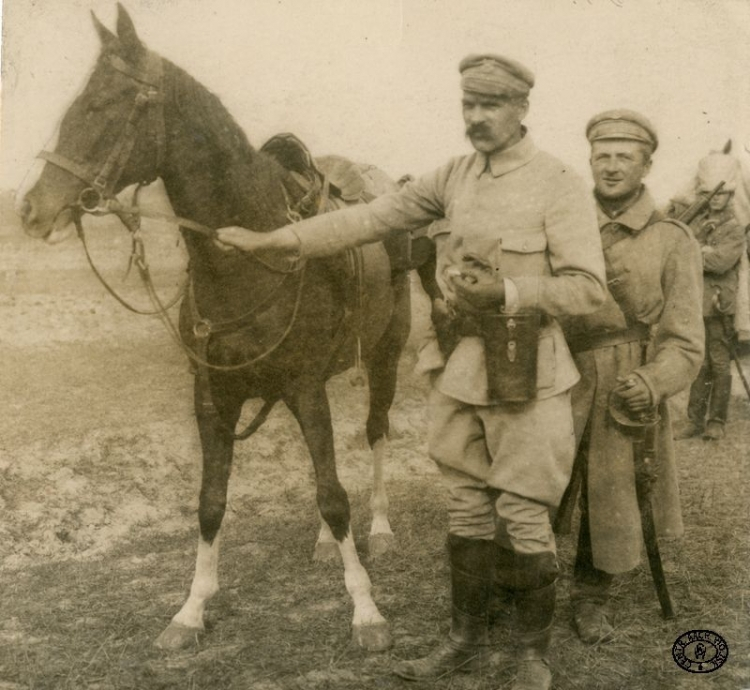 Komendant Józef Piłsudski z Kasztanką nad Nidą. Obok stoi ordynans Szymkiewicz. Wiosna, 1915 r. Źródło: CAW