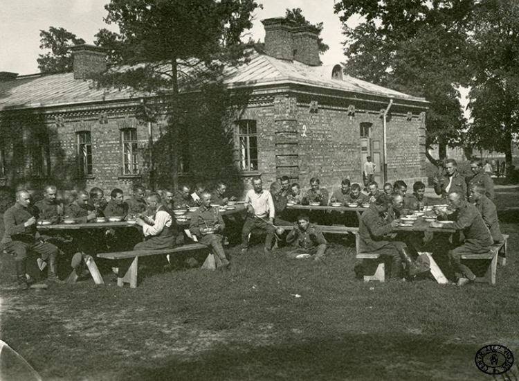 Ordynansi oficerów legionowych podczas posiłku w obozie internowanych w Beniaminowie. Lato 1917 r. Źródło: CAW