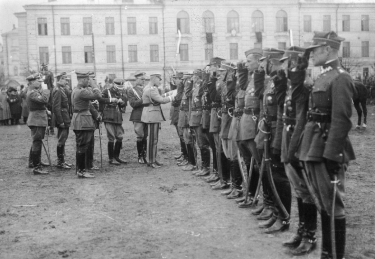 Marszałek Jóżef Piłsudski odznacza żołnierzy. Wśród oficerów stojących za marszałkiem widać m.in. płk Juliusz Rómmel (1. z lewej) i mjr Bogusław Miedziński (2. z lewej), 1920. Źródło: NAC