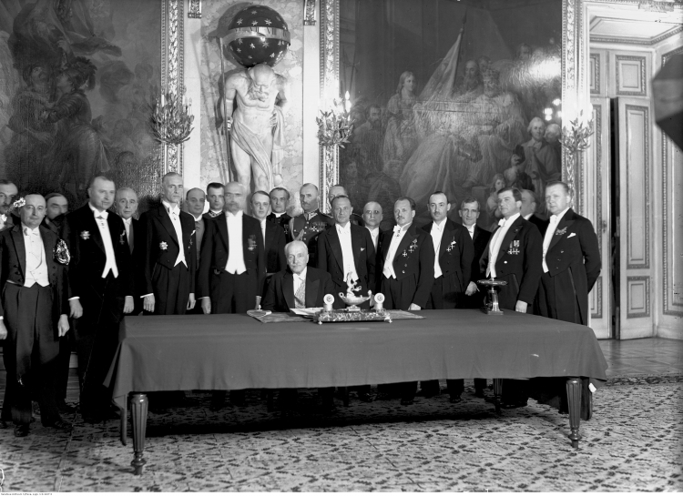 23 04 1935. Warszawa. Zamek Królewski, Sala Rycerska. Widoczni m.in. premier W. Sławek, M. Z. Kościałkowski, płk J. Głogowski, S. Świeżawski, wicemarszałek Sejmu S. Car, marszałek Sejmu K. Świtalski, marszałek Senatu W, Raczkiewicz, K. Romer (na prawo za W. Raczkiewiczem), M. Butkiewicz, E. Kaliński, H. Floyar-Rajchman (2. z lewej), J. Paciorkowski, J. Poniatowski, W. Jędrzejewicz, ks. J Humpola (stoi w głębi za prezydentem), kpt. J. Hartman (w głębi, na prawo za K. Romerem). Źródło: NAC 23 04 1935. Warszawa. Zamek Królewski, Sala Rycerska. Widoczni m.in. premier W. Sławek, M. Z. Kościałkowski, płk J. Głogowski, S. Świeżawski, wicemarszałek Sejmu S. Car, marszałek Sejmu K. Świtalski, marszałek Senatu W, Raczkiewicz, K. Romer (na prawo za W. Raczkiewiczem), M. Butkiewicz, E. Kaliński, H. Floyar-Rajchman (2. z lewej), J. Paciorkowski, J. Poniatowski, W. Jędrzejewicz, ks. J Humpola (stoi w głębi za prezydentem), kpt. J. Hartman (w głębi, na prawo za K. Romerem). Źródło: NAC